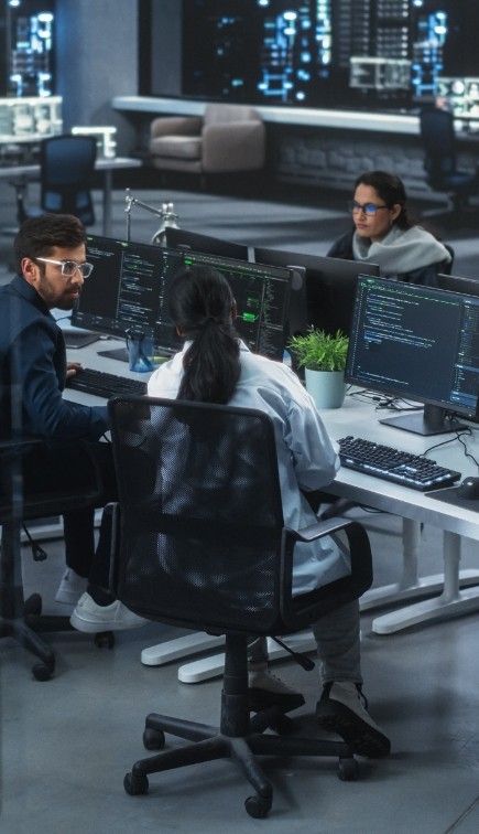 Equipo de consultores tecnológicos analizando código y sistemas en estaciones de trabajo, representando asesoría especializada en ciberseguridad, calidad y tecnologías de la información para empresas.
